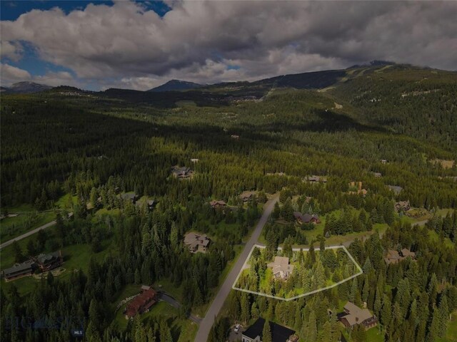 83 W Pine Cone Ter, Big Sky, MT 59716 - aerial overview of property's location featuring a forest, property parcel outlined, and a mountainous background
