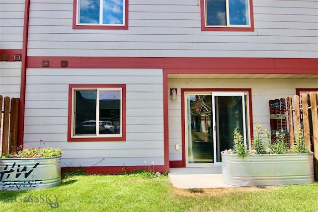 rear view of property featuring a yard and fence