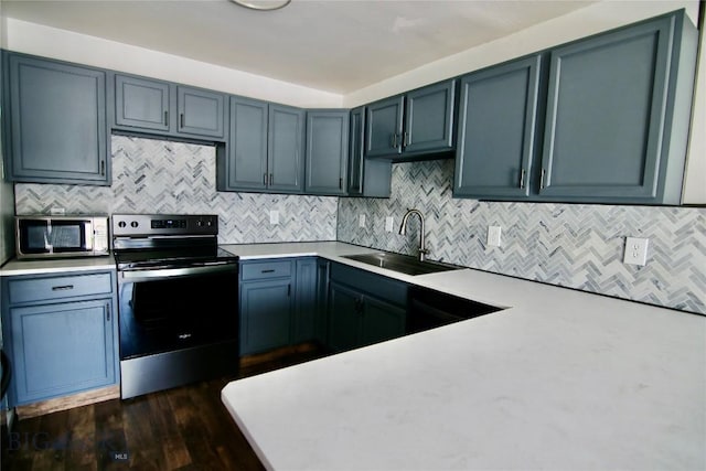 kitchen with tasteful backsplash, appliances with stainless steel finishes, light countertops, and a sink