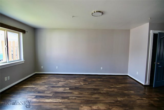 spare room featuring dark wood-style floors and baseboards