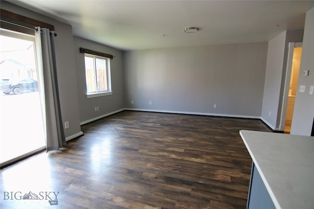 unfurnished room with baseboards and dark wood-style flooring