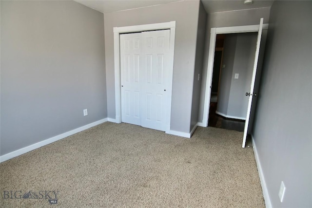 unfurnished bedroom with carpet, a closet, and baseboards