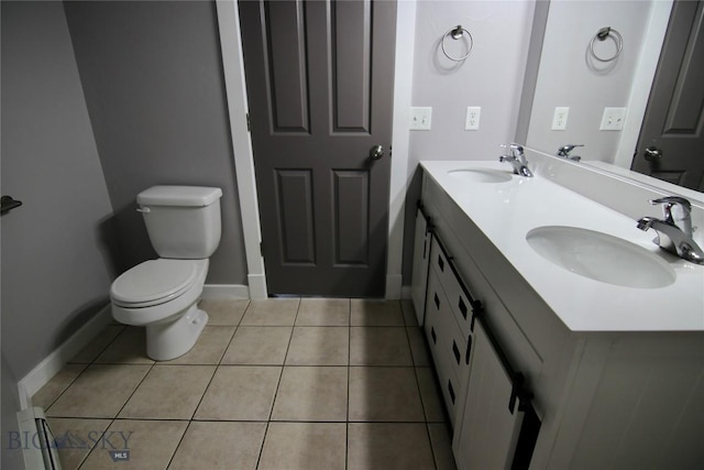 full bath with toilet, tile patterned flooring, double vanity, and a sink