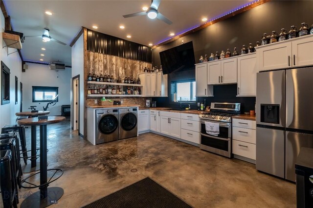 kitchen with appliances with stainless steel finishes, washer and dryer, wooden counters, white cabinetry, and ceiling fan