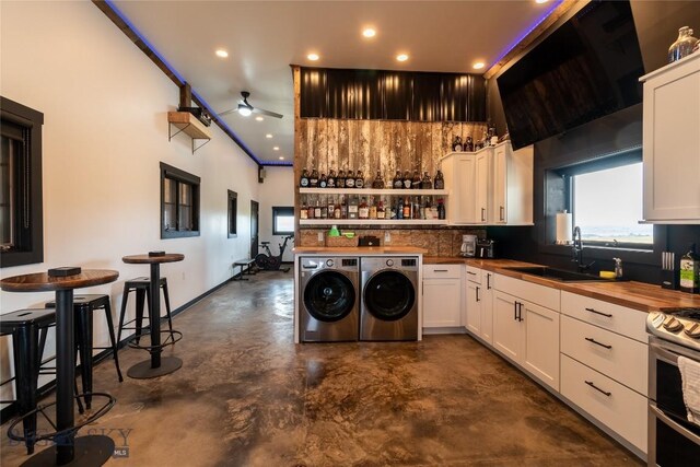 kitchen featuring butcher block counters, double oven range, sink, white cabinets, and separate washer and dryer