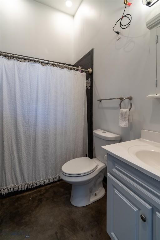 bathroom with toilet, concrete floors, and vanity