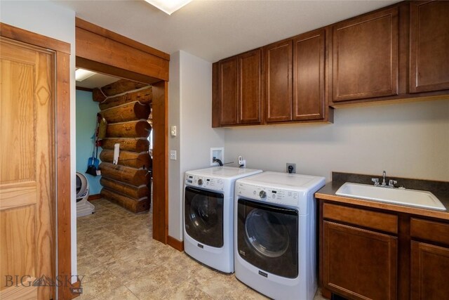 clothes washing area with sink, cabinets, log walls, and washer and dryer