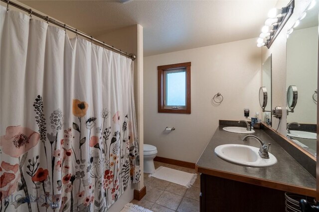 bathroom with tile patterned floors, toilet, vanity, and walk in shower