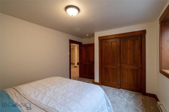 carpeted bedroom with a closet and a baseboard heating unit