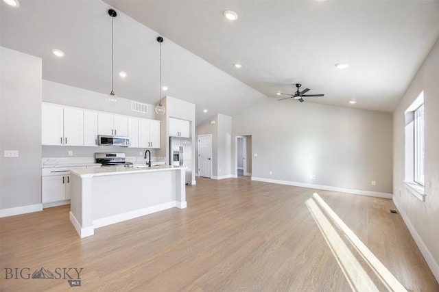 kitchen with a center island with sink, appliances with stainless steel finishes, ceiling fan, white cabinets, and decorative light fixtures