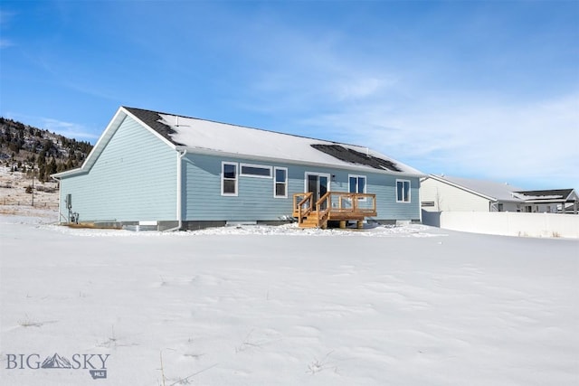 snow covered rear of property with a deck