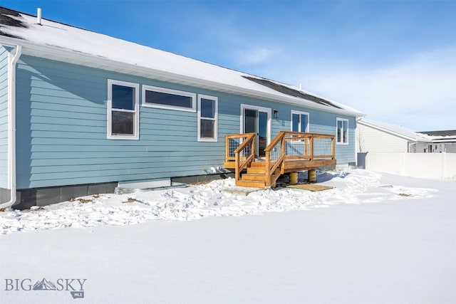 snow covered back of property featuring a deck