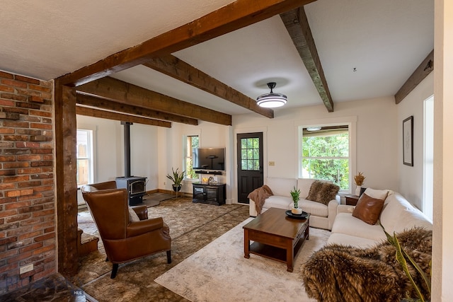 living room featuring beamed ceiling, brick wall, and a wood stove