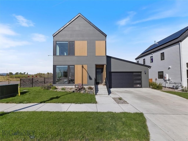 modern home with concrete driveway, a front yard, fence, and a garage