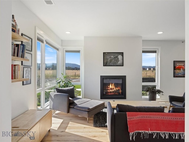 interior space featuring visible vents, a glass covered fireplace, wood finished floors, and recessed lighting