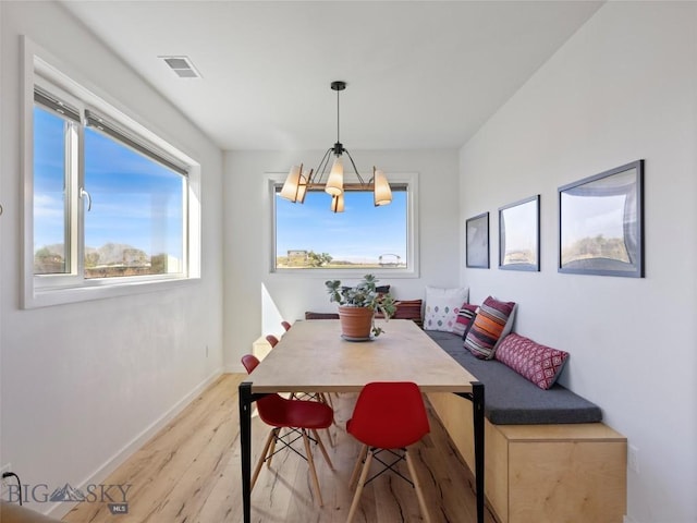 dining room featuring baseboards, an inviting chandelier, light wood finished floors, and visible vents