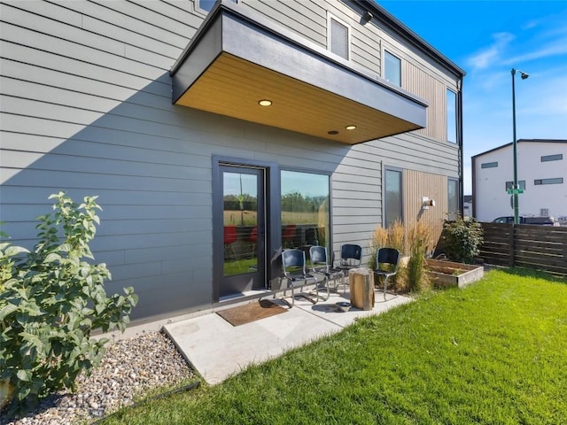 back of property with fence, a patio area, and a yard