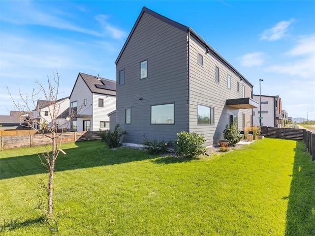 back of house featuring a lawn, a residential view, and a fenced backyard