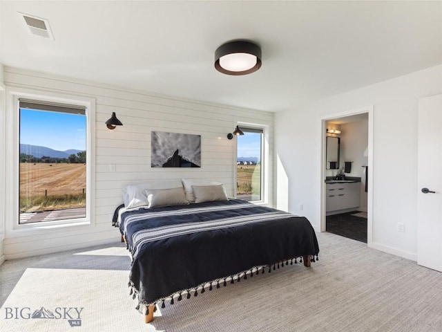 bedroom featuring baseboards, visible vents, a mountain view, light colored carpet, and ensuite bath