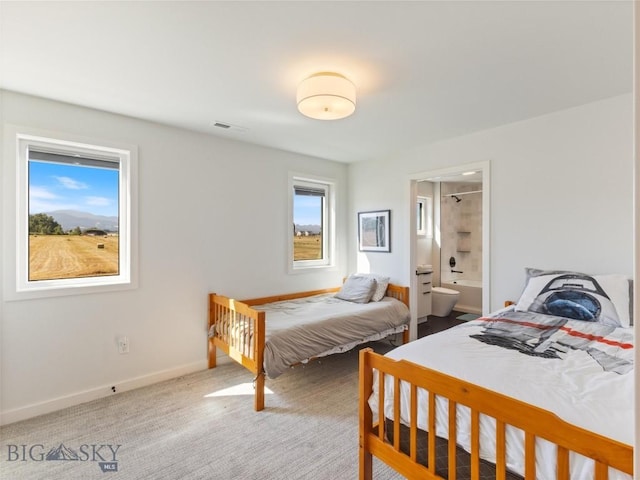 bedroom with carpet floors, baseboards, visible vents, and ensuite bath