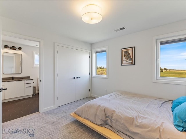 bedroom featuring a closet, multiple windows, light colored carpet, and visible vents