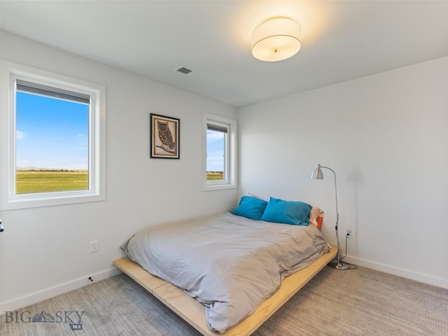 bedroom with baseboards, visible vents, and light carpet