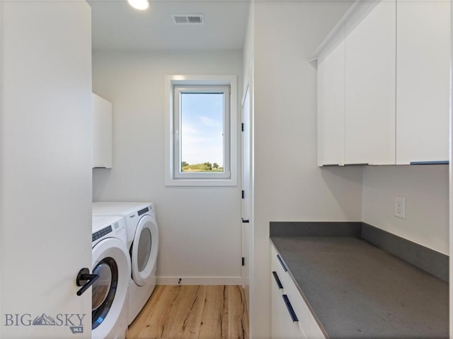 clothes washing area with light wood-style flooring, visible vents, washing machine and clothes dryer, baseboards, and cabinet space