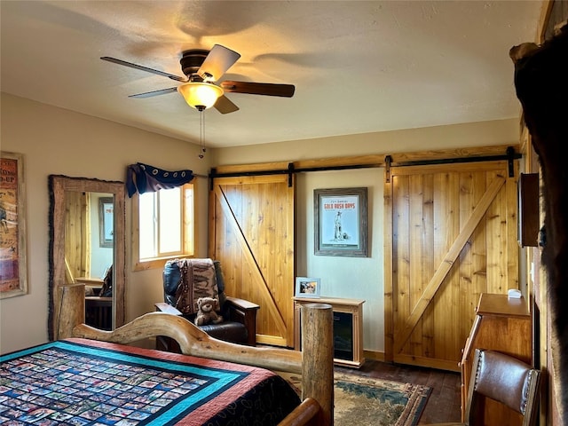 bedroom featuring wood walls, ceiling fan, hardwood / wood-style flooring, and a barn door