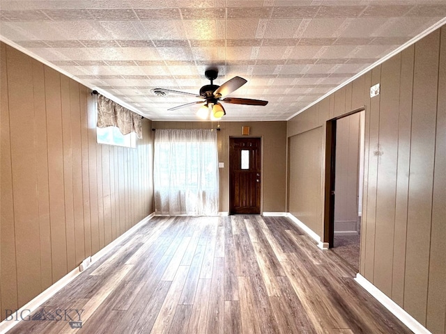 foyer entrance with hardwood / wood-style floors, ceiling fan, wood walls, and crown molding