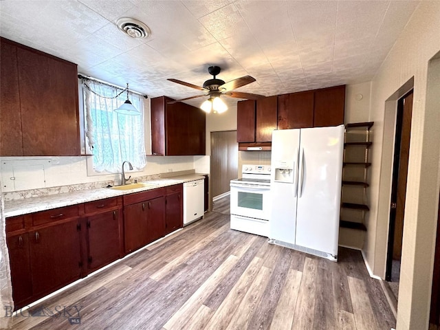 kitchen with white appliances, sink, hanging light fixtures, ceiling fan, and light wood-type flooring