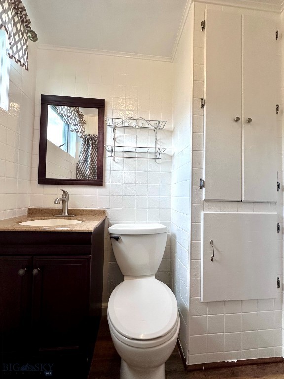 bathroom featuring vanity, toilet, tile walls, and ornamental molding