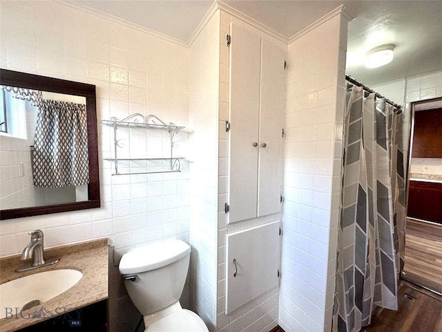 bathroom featuring vanity, wood-type flooring, ornamental molding, and tile walls