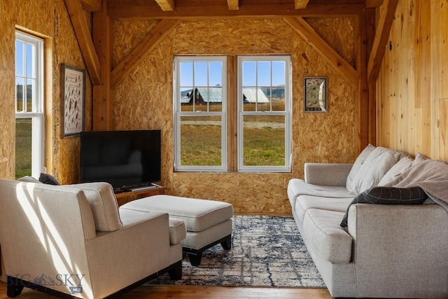 living room with wooden walls, lofted ceiling with beams, and wood-type flooring