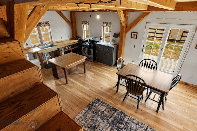 living room with light wood-type flooring, french doors, and lofted ceiling with beams