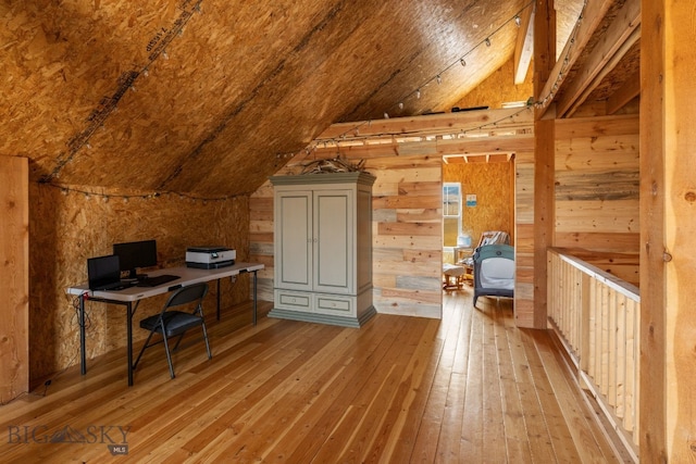 office featuring light wood-type flooring, wooden walls, and lofted ceiling