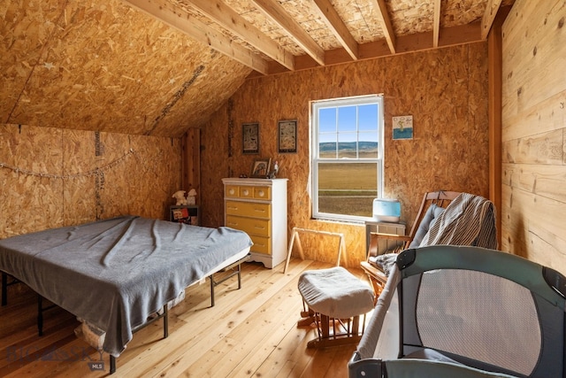 bedroom featuring light hardwood / wood-style flooring and lofted ceiling with beams