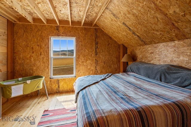 unfurnished bedroom with hardwood / wood-style flooring and vaulted ceiling