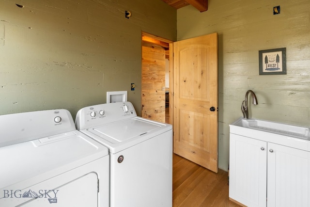 laundry area with sink, wood walls, light hardwood / wood-style floors, and independent washer and dryer