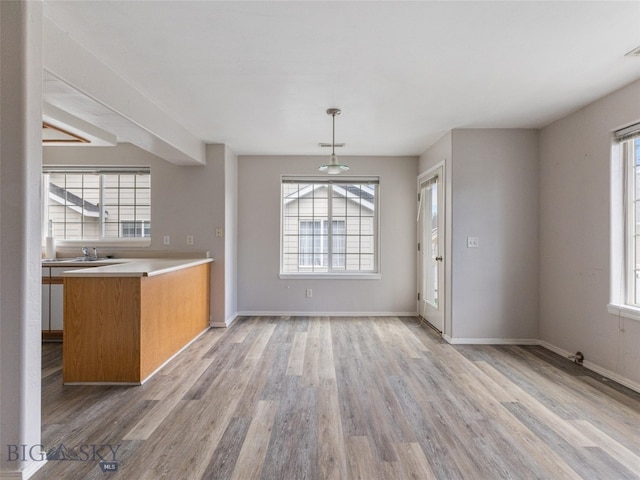 kitchen with kitchen peninsula, decorative light fixtures, and hardwood / wood-style floors