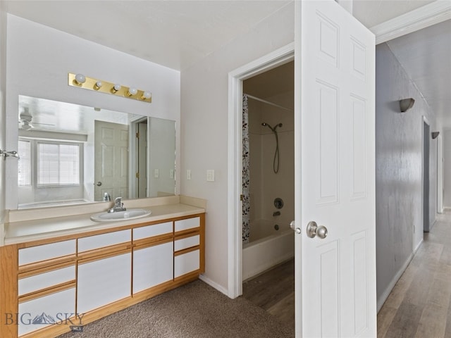 bathroom featuring ceiling fan, hardwood / wood-style flooring, tiled shower / bath combo, and vanity