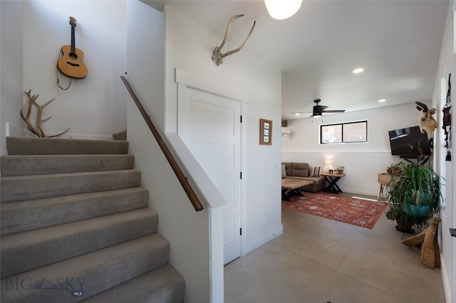 stairway featuring ceiling fan and concrete flooring