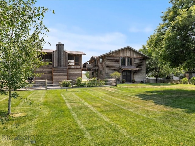 back of house featuring a yard, a chimney, and fence