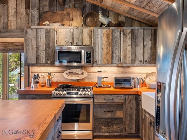 kitchen with a toaster, wood ceiling, butcher block countertops, appliances with stainless steel finishes, and vaulted ceiling