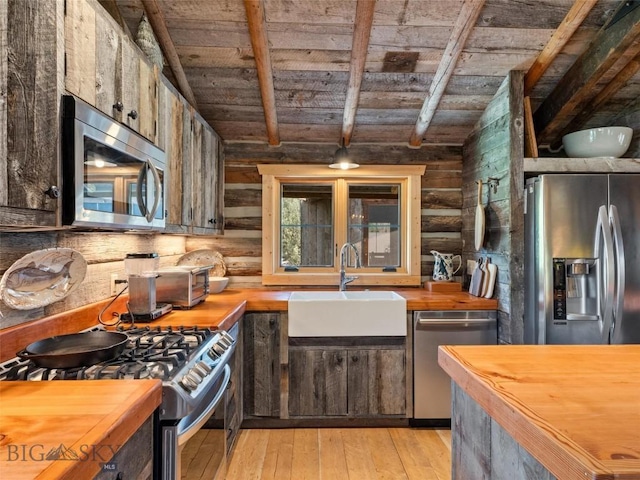 kitchen with a sink, wood ceiling, wooden counters, appliances with stainless steel finishes, and light wood-type flooring