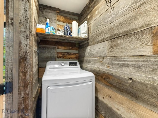 clothes washing area featuring washer / clothes dryer, wood walls, and laundry area