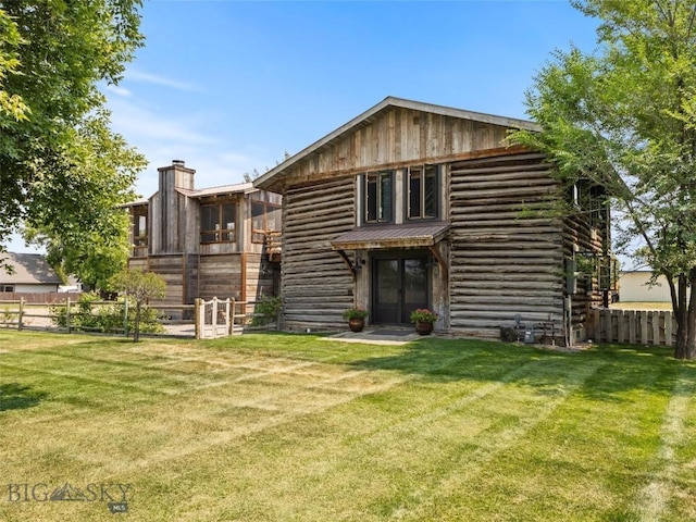 rear view of house featuring a yard, metal roof, fence, and a chimney