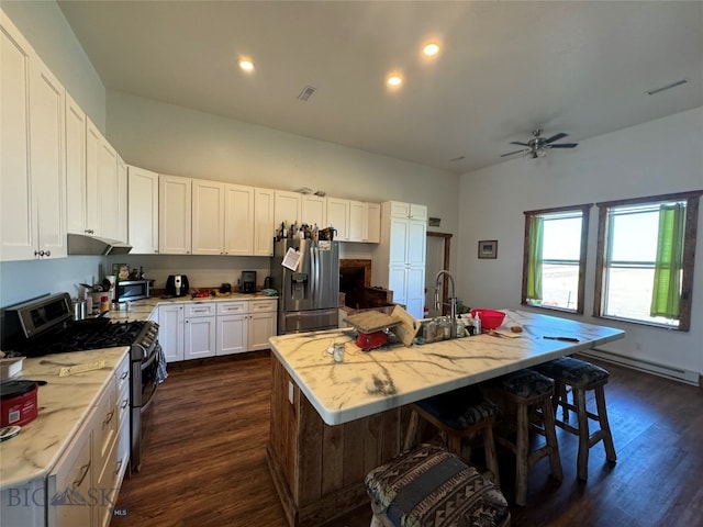 kitchen with a baseboard heating unit, an island with sink, dark hardwood / wood-style flooring, white cabinetry, and stainless steel appliances