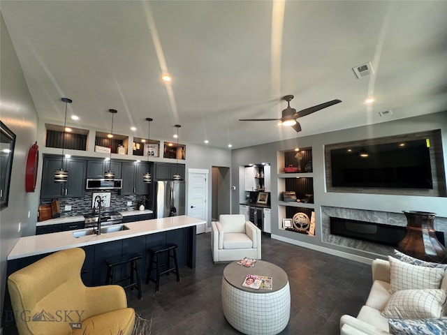 living room featuring dark wood-type flooring, sink, ceiling fan, built in features, and a premium fireplace