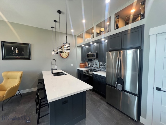 kitchen with a kitchen bar, appliances with stainless steel finishes, a kitchen island with sink, sink, and decorative light fixtures