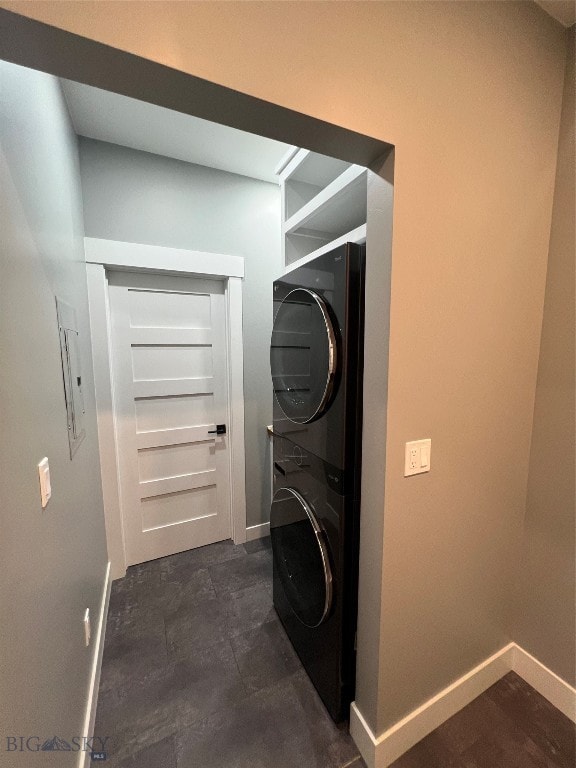 clothes washing area featuring electric panel and stacked washer and dryer